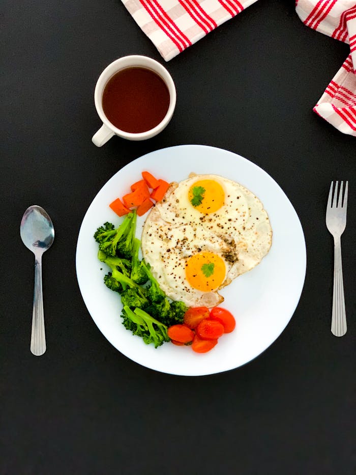 Mastering the First Impression: Your intriguing post title goes here A nutritious breakfast featuring fried eggs, veggies, and tea on a clean black background.