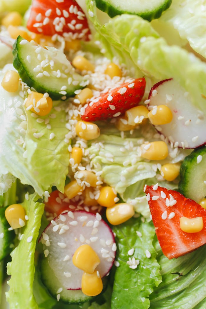 A vibrant close-up of fresh salad with vegetables, strawberries, and sesame seeds.