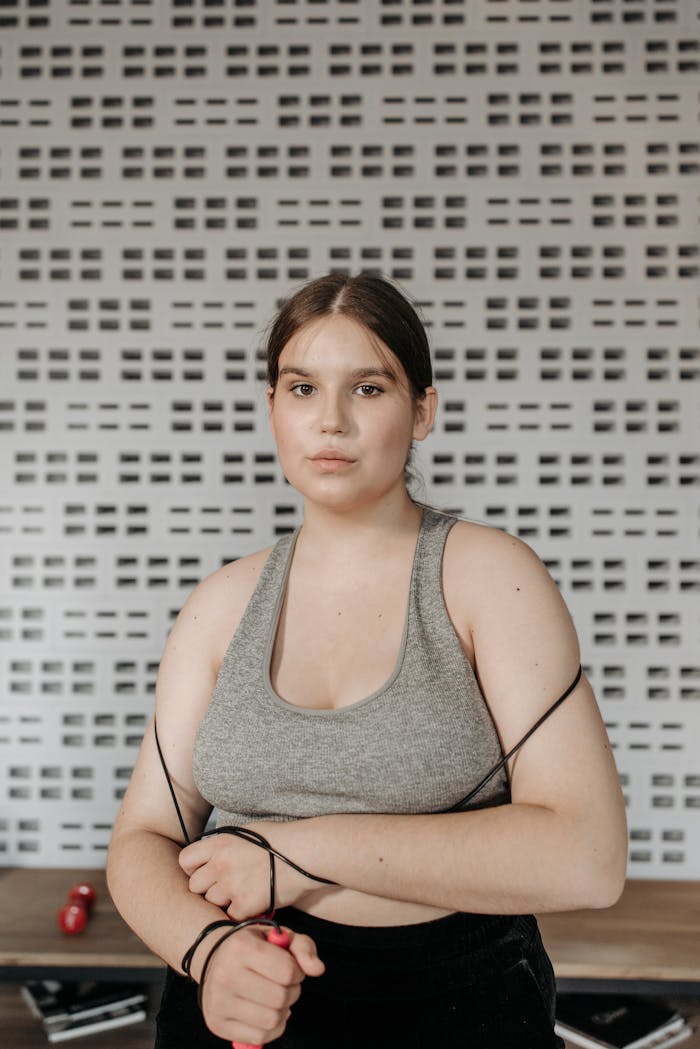 services-01 Confident woman in athletic wear holding a jump rope indoors, ready for fitness.